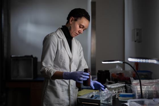 Photo of a woman in a white lab coat, working in a laboratory